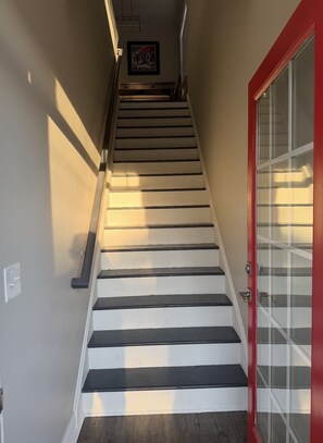 Stairs lead to an upper floor, flanked by light beige walls and a red door.