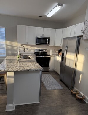 Enjoy cooking in this well-equipped kitchen with a granite countertop island, sink, and stainless steel appliances.