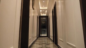 Ein langer, schmaler Hotelkorridor mit Marmorboden und eingelassener Beleuchtung an der Decke.