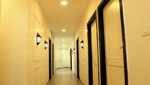 A hotel hallway with patterned flooring, doors, and wall-mounted lights. - Hotel Indra Palace (Udaipur)