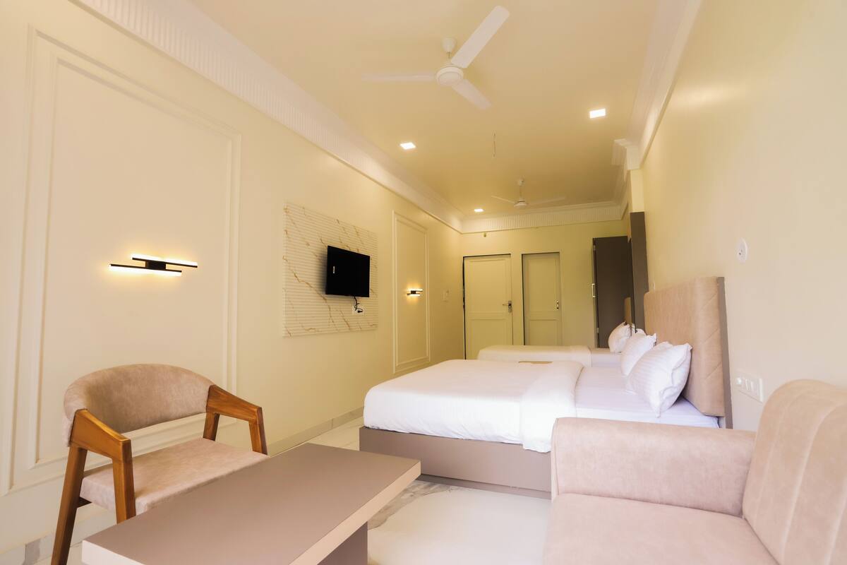 A hotel room with a bed, a chair, a table, and a ceiling fan.