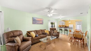 A living room with a sofa, armchairs, a glass coffee table, and a dining area with chairs and a table. - 3-Bed with pool - Close to beach (Melbourne)