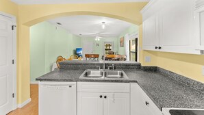 A kitchen with white cabinets, a granite countertop, and a double sink. - 3-Bed with pool - Close to beach (Melbourne)
