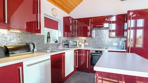 Una cocina moderna con armarios rojos, microondas, tostadora y pileta.
