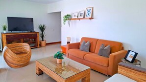 Ein modernes Wohnzimmer mit einer Couch, einem Couchtisch, einem Fernseher und Zimmerpflanzen.
