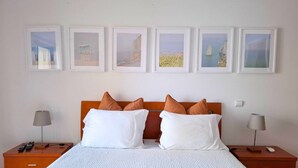 Ein Hotelzimmer mit einem Bett, zwei Nachttischen und vier gerahmten Bildern an der Wand.