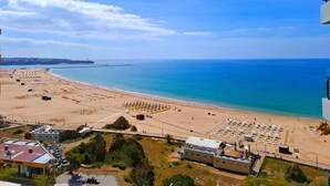 Ein Strand mit Parkplatz, ein Gebäude mit rotem Dach und freier Meerblick.