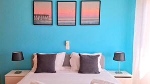 A hotel room with a large bed, two nightstands, and three framed pictures on the wall.