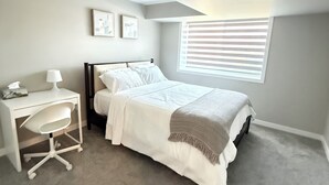 Une chambre à coucher avec un lit, un bureau et une fenêtre avec des stores.
