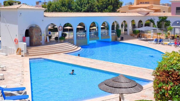 Una gran piscina al aire libre con múltiples arcos y zonas de descanso.
