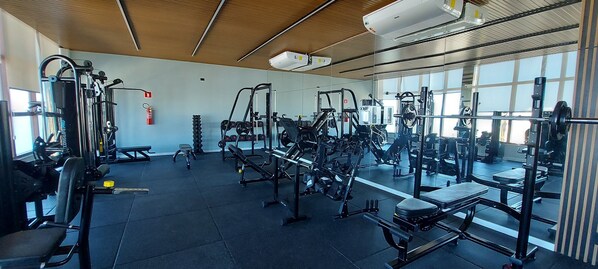 A gym with various exercise equipment, large windows, and a ceiling with ventilation.