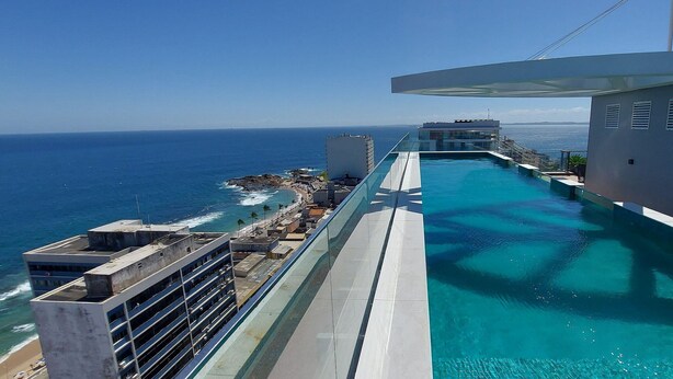 A pool with a view of the ocean and a building in the background.