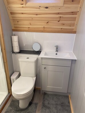 A compact bathroom with a toilet, sink, and mirror. - Starview by Mirriemora l Shetland l St Ninians Isle l Cosy Pod (Bigton)