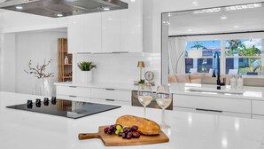 A modern kitchen with a central island, white cabinetry, and a large window offering a view of the outdoors.