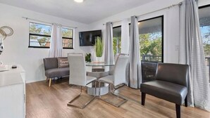A modern living room with a glass dining table, grey sofa, and a leather armchair. - Bradenton Breeze  (Bradenton)