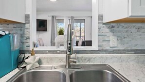 A modern kitchen with a double sink, a stainless steel faucet, and a backsplash with patterned tiles. - Bradenton Breeze  (Bradenton)