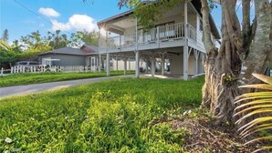A two-story house with a balcony, surrounded by lush greenery and a white picket fence. - Bradenton Breeze  (Bradenton)