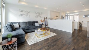Ein modernes Wohnzimmer mit einem grauen Sofa, einem Couchtisch und einem gemusterten Teppich.