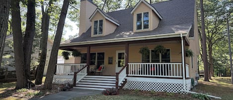 A two-story house with a porch, a front door, and a small staircase leading to the entrance.