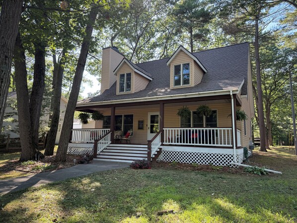 A two-story house with a porch, a front door, and a small staircase leading to the entrance.