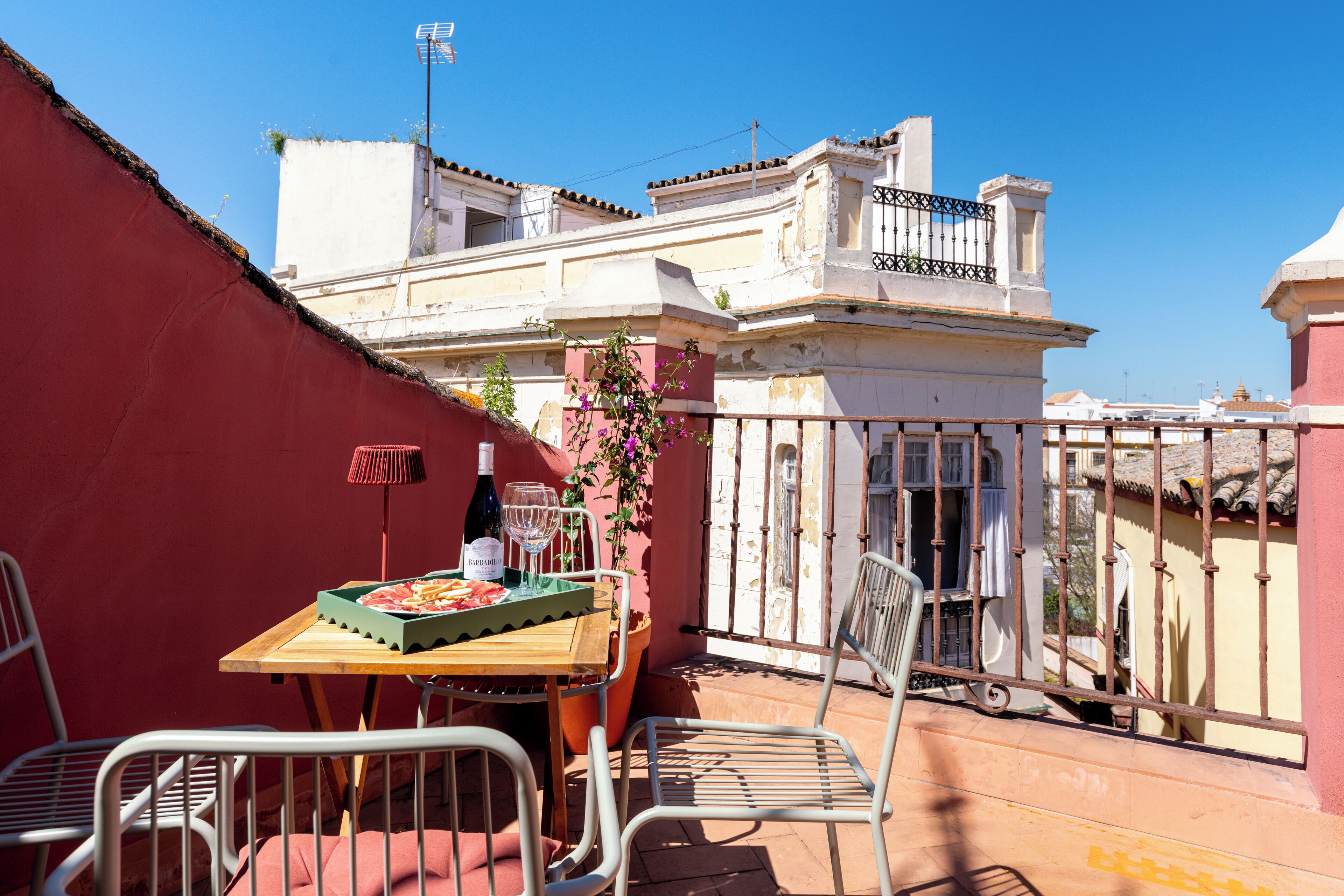 Eine Terrasse mit Holztisch, Stühlen und einer Weinflasche.