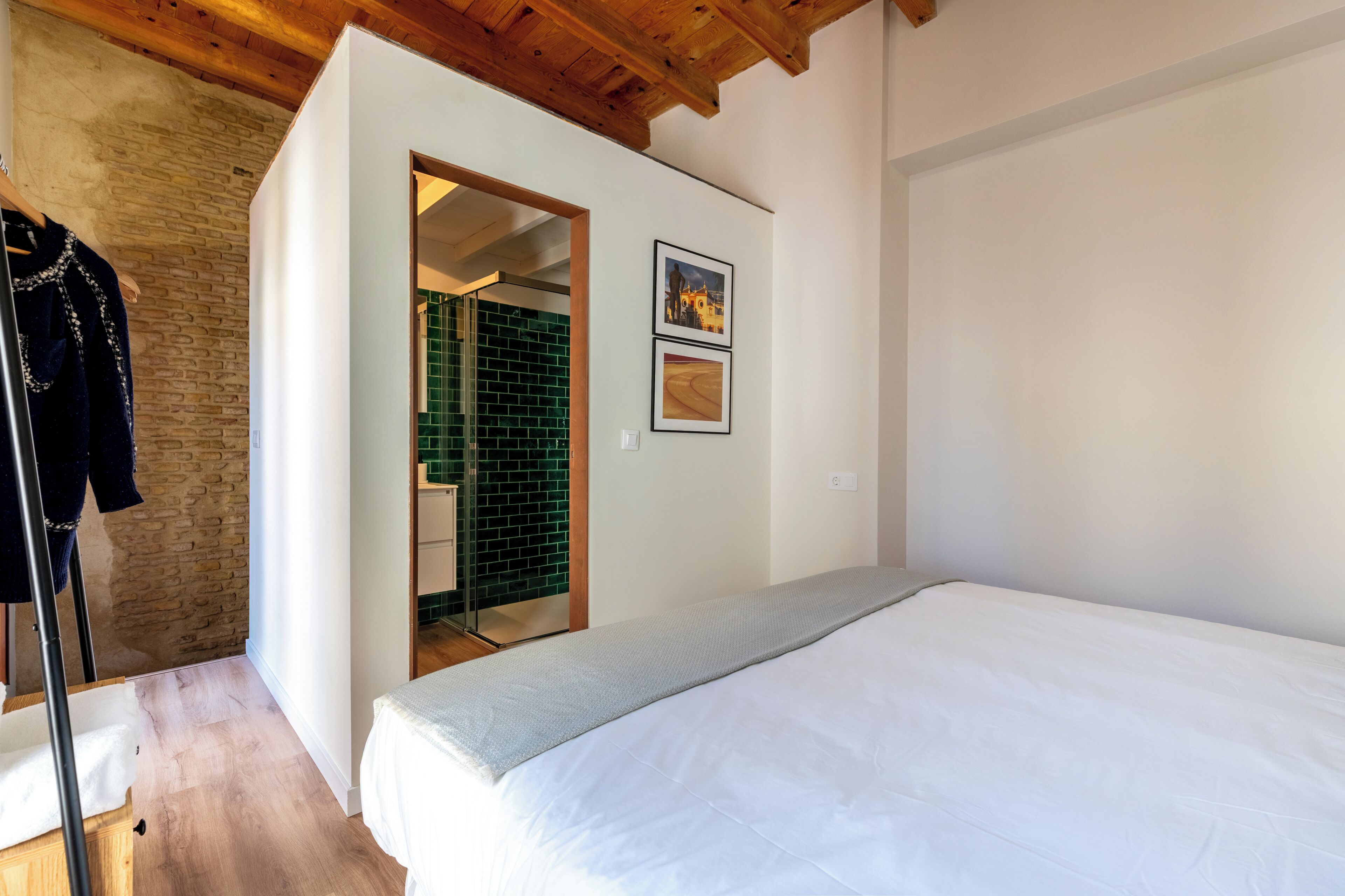 Une chambre à coucher avec un lit, un plafond en bois, un mur en briques et une porte donnant sur une autre pièce.