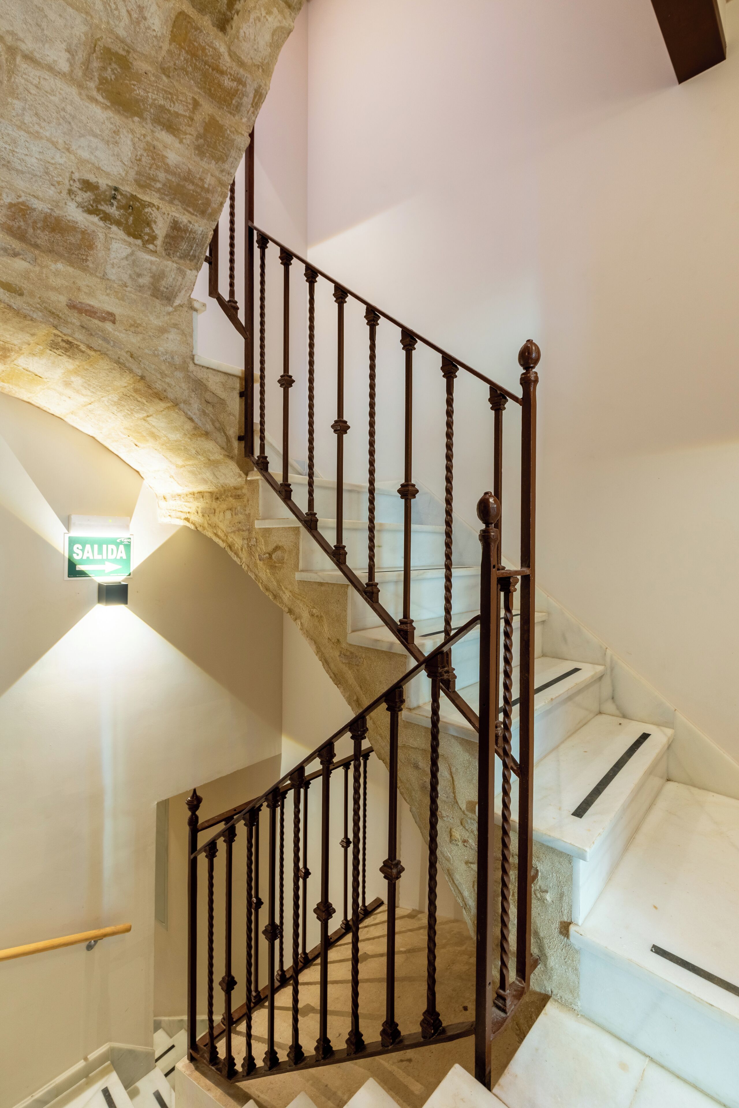 Eine Treppe mit schmiedeeisernem Geländer, einer Steinmauer und einem Schild, das einen Ausgang zeigt.