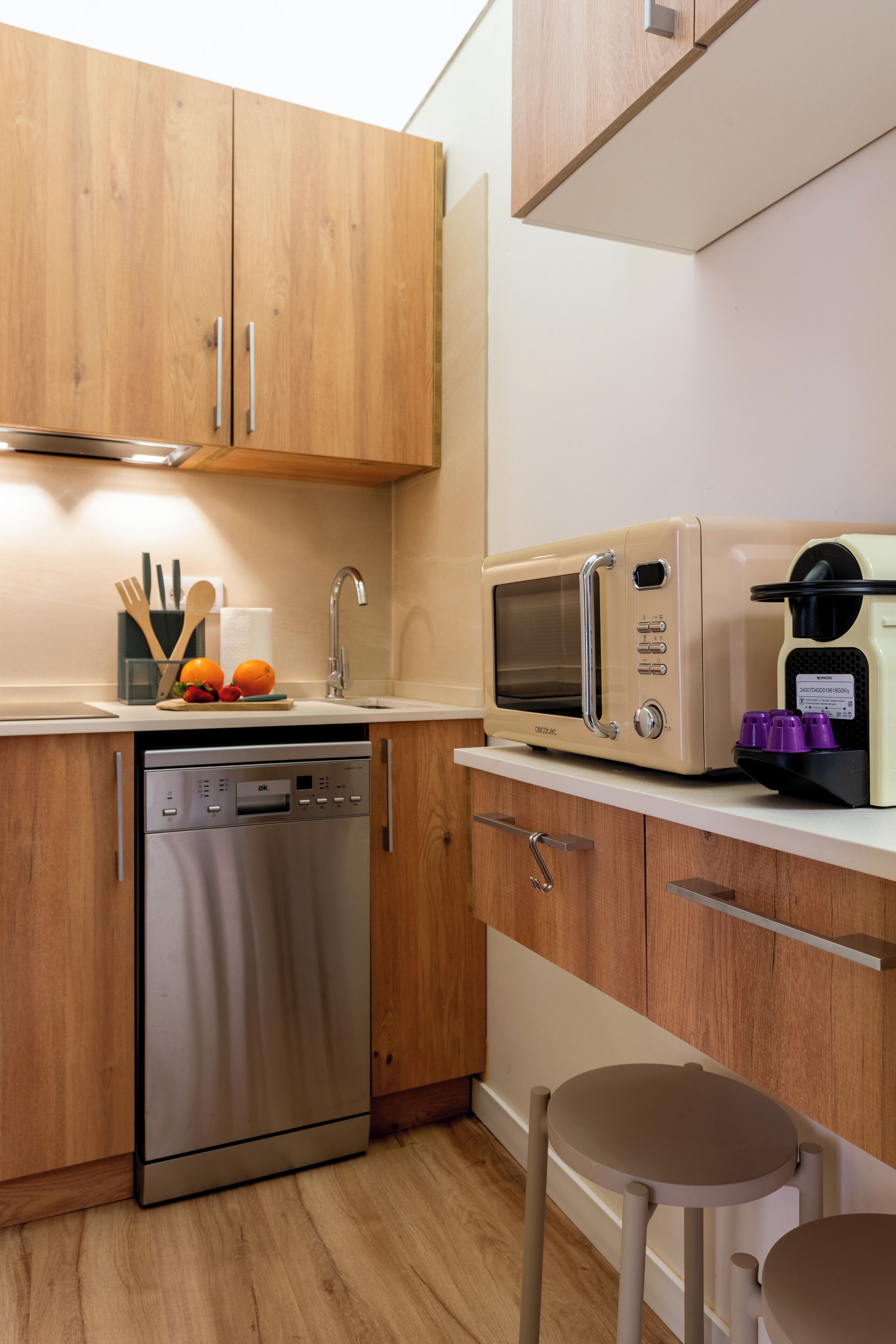 Une cuisine moderne avec des meubles en bois, un lave-vaisselle en acier inoxydable, un four à micro-ondes et une machine à café.