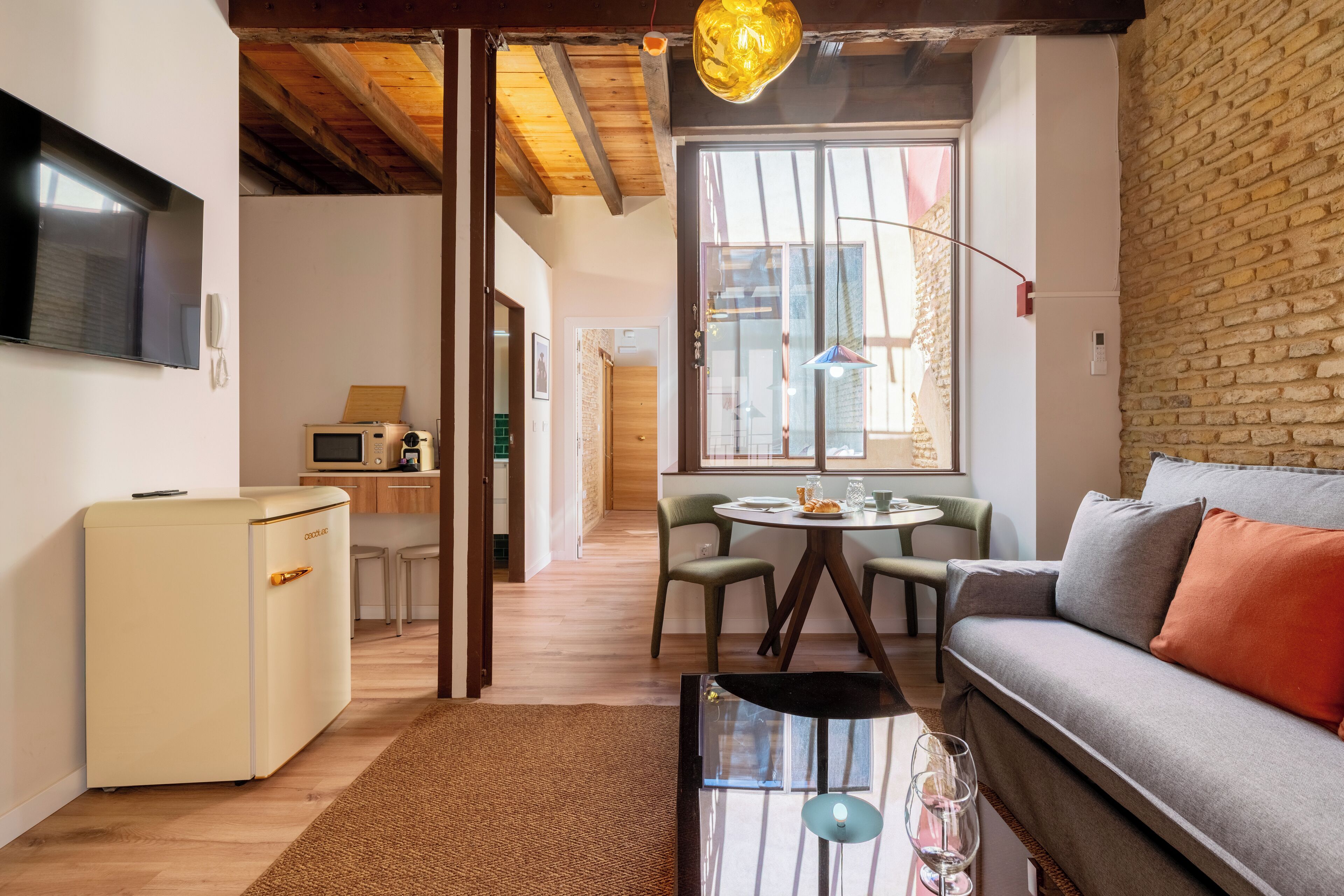 A compact living space with a kitchenette, a dining area, and a seating area with a sofa and chairs.