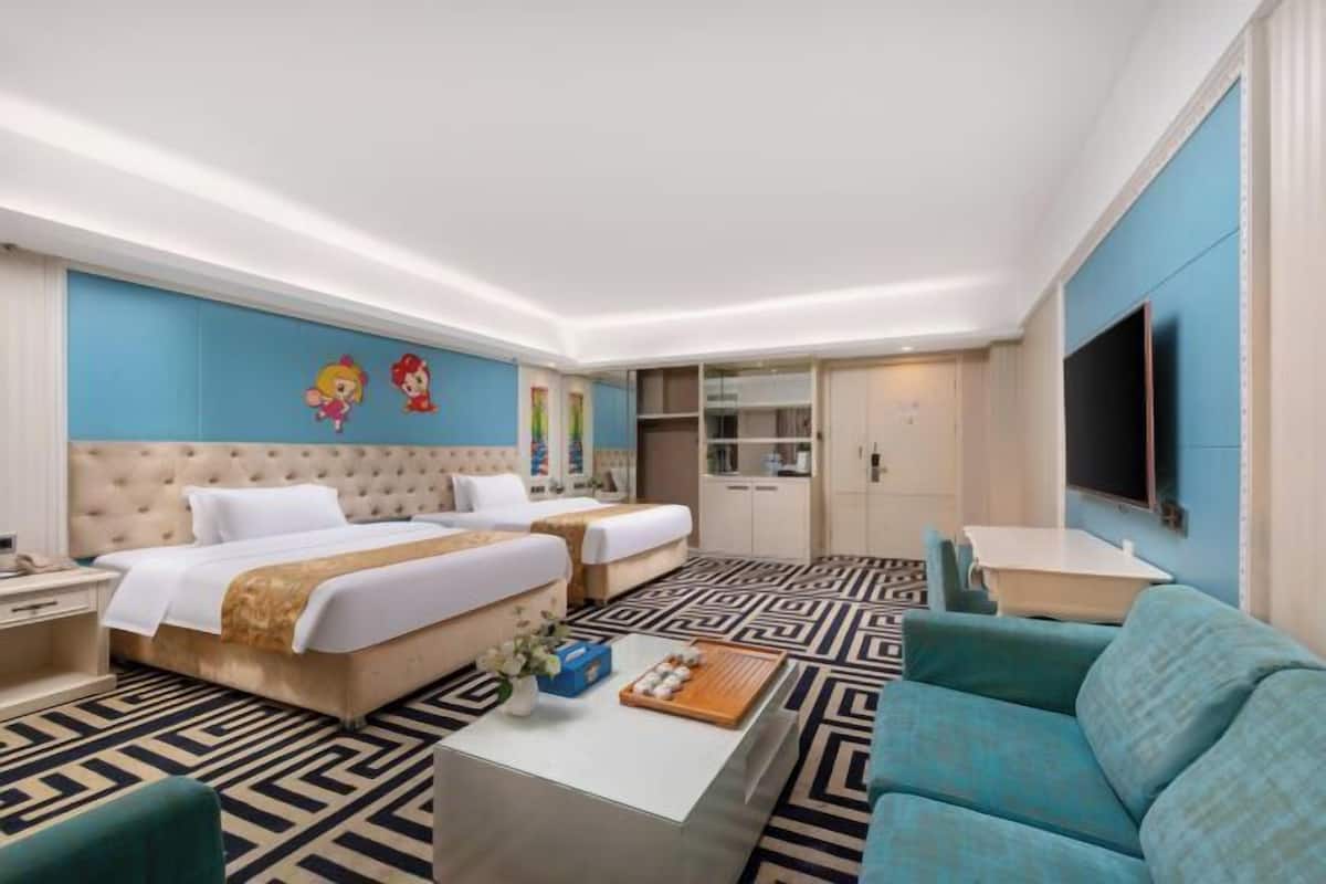 Habitación de hotel con dos camas, un sofá, una mesa de centro, un televisor y un minibar.