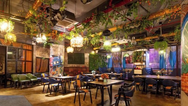 A restaurant with tables and chairs, hanging plants, and a mural on the wall. - Longtai Jindu Hotel (Huizhou Ganghui Shopping Center) (Huizhou)