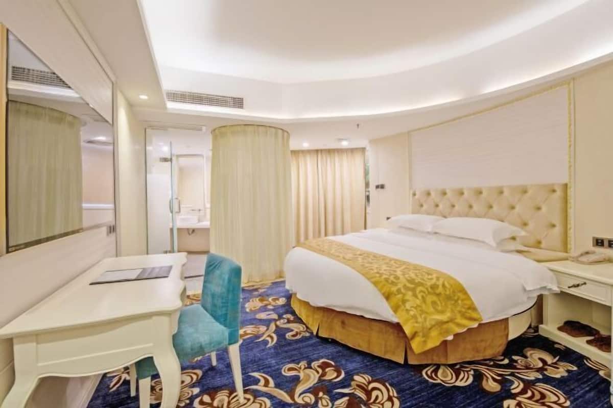 Una habitación de hotel con cama, escritorio, silla y espejo.