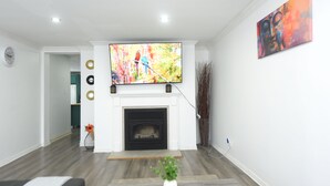Un salon doté d’une cheminée, d’un téléviseur à écran plat fixé au-dessus et d’un tableau accroché au mur.