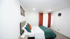 Une chambre à coucher avec un lit, une table de chevet, une horloge murale et une fenêtre avec des rideaux.