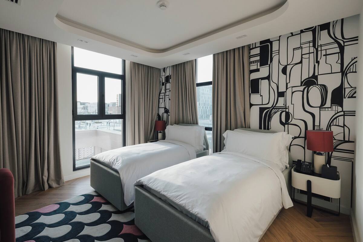 Ein Hotelzimmer mit zwei Betten, Blick auf die Stadt, einem gemusterten Wanddesign und einem modernen Stil.