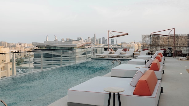 A rooftop pool area with lounge seating and a city view. - The Muse Hotel  (Lusail)