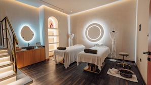 A spa room with two treatment beds, a reception desk, and a staircase. - The Muse Hotel  (Lusail)