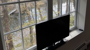 Un televisor en un alféizar con vista a árboles y un río.