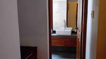 A hallway leading to a bathroom with a sink and mirror.