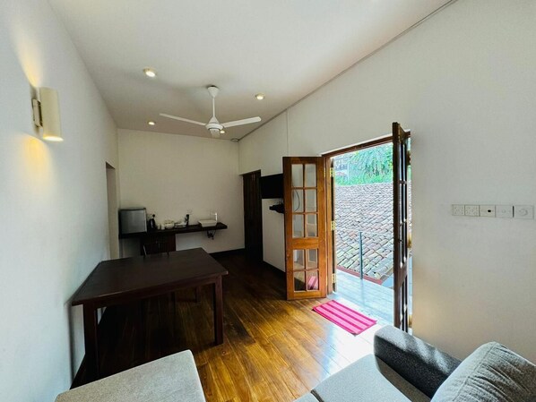 Amplia habitación con una mesa de comedor de madera, un sofá y un gran ventanal corredero que da a un espacio exterior.