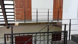 A multi-level building with wooden doors, a metal staircase, and a metal railing. - Crips Hill Apartments (Galle)