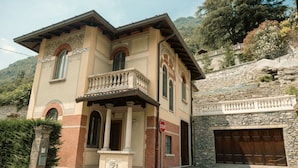 A two-story building with a balcony, a stone wall, and a garage.