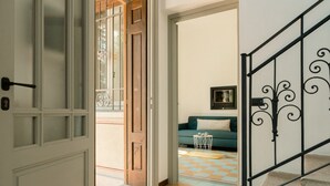 A hallway with a wooden door, a checkered floor, a sofa, and a small table.