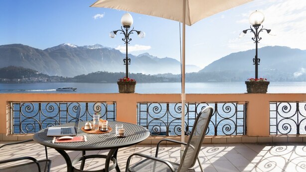 A terrace with a round table, chairs, and a laptop.