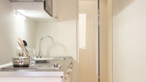 Ett modernt kök med en diskho i rostfritt stål, en kastrull på bänkskivan och ett glas vatten.