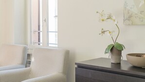 A room with a checkered sofa, a dark wooden side table, a potted orchid, and a window with a view.