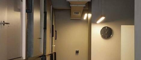 A narrow hallway with a reception desk on the right, featuring a clock and a stone accent wall.
