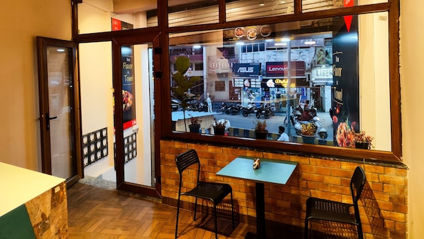 A restaurant with a brick wall and a window view of the street. - C2 PODS (Varanasi)