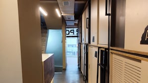A hallway with lockers, a reception desk, and a staircase leading to an upper level. - C2 PODS (Varanasi)
