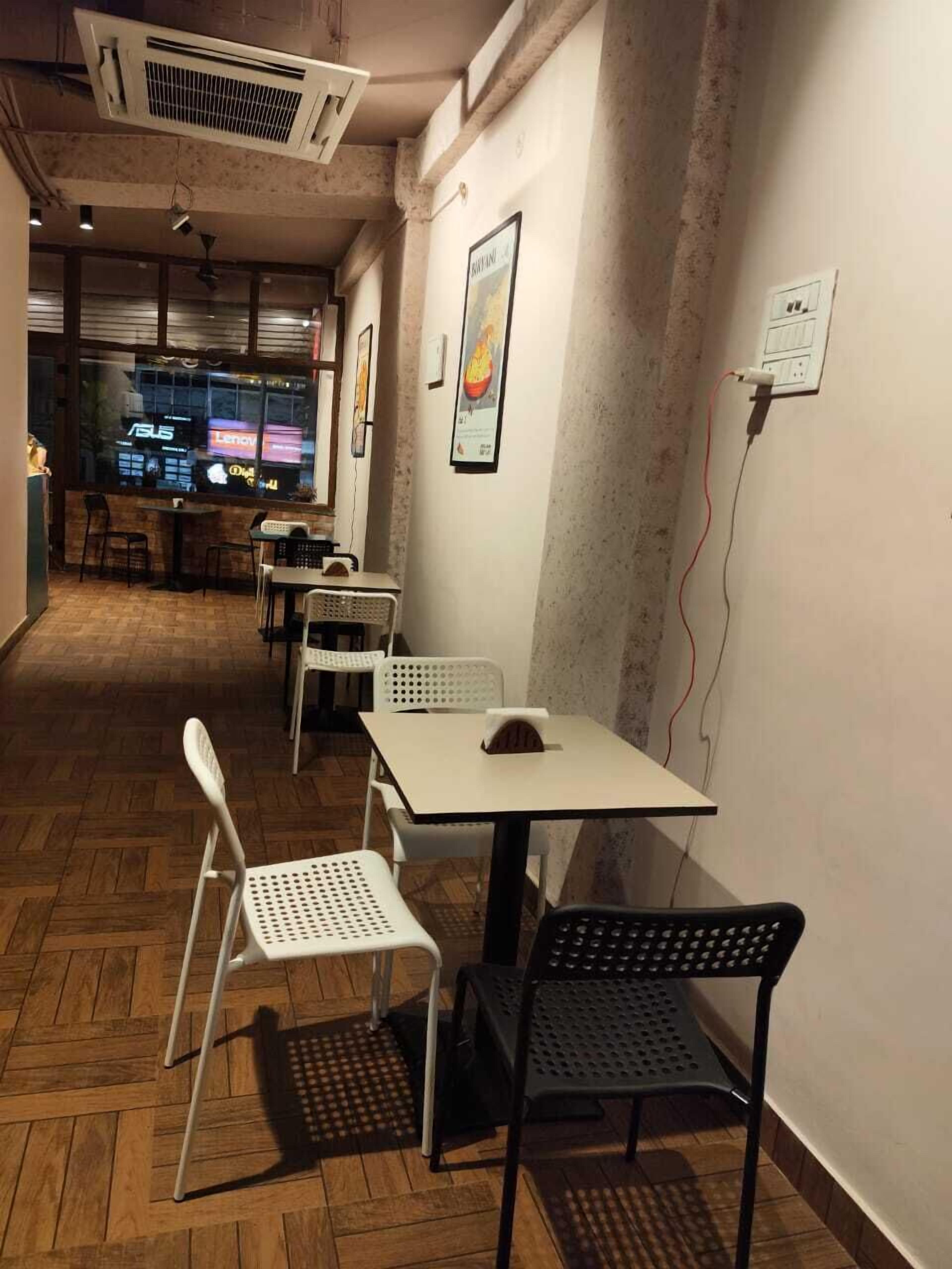 A corridor with tables and chairs, a wall-mounted air conditioner, and a poster.